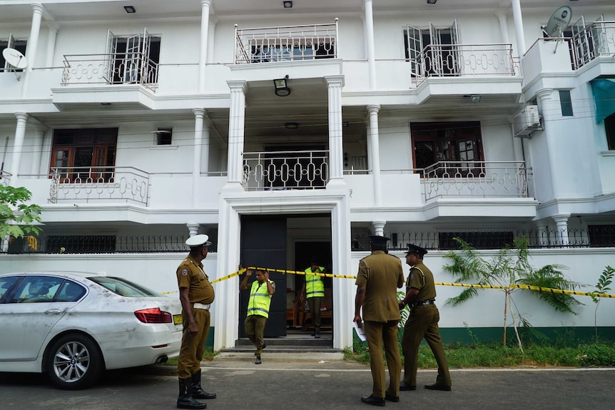 Sri Lankan police outside a big white house.