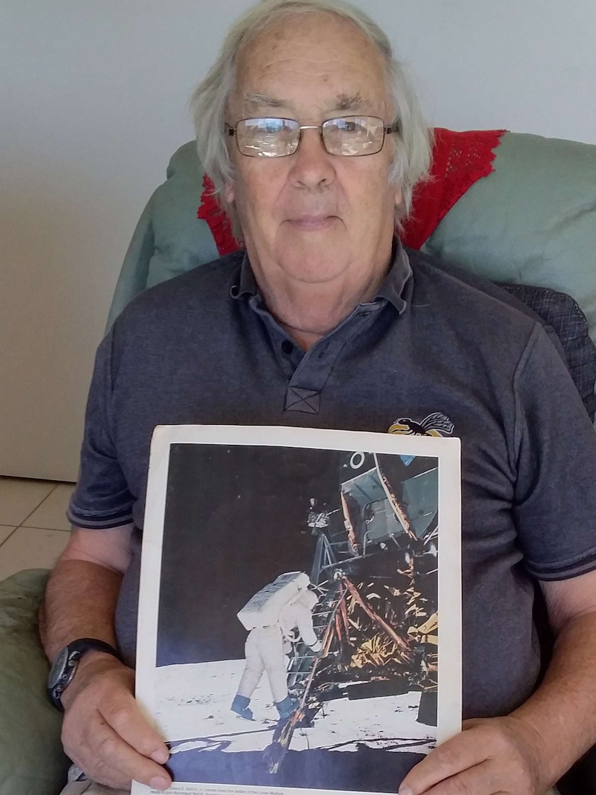 A man holds a photo of Neil Armstrong on the moon