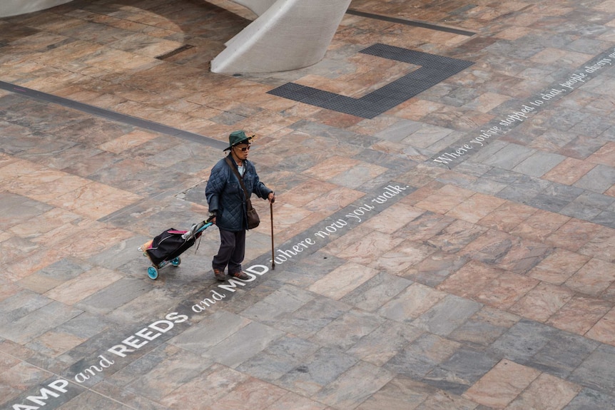 A lone pedestrian walks through a deserted public meeting space in Perth's CBD.