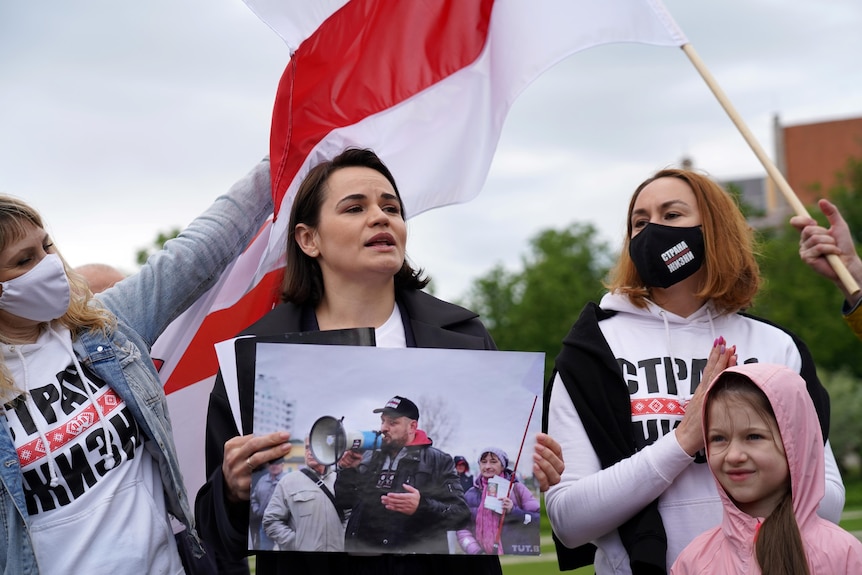 A woman holds a picture of husband at a protest.