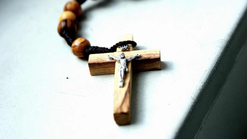 A small cross attached to beads lying on a table