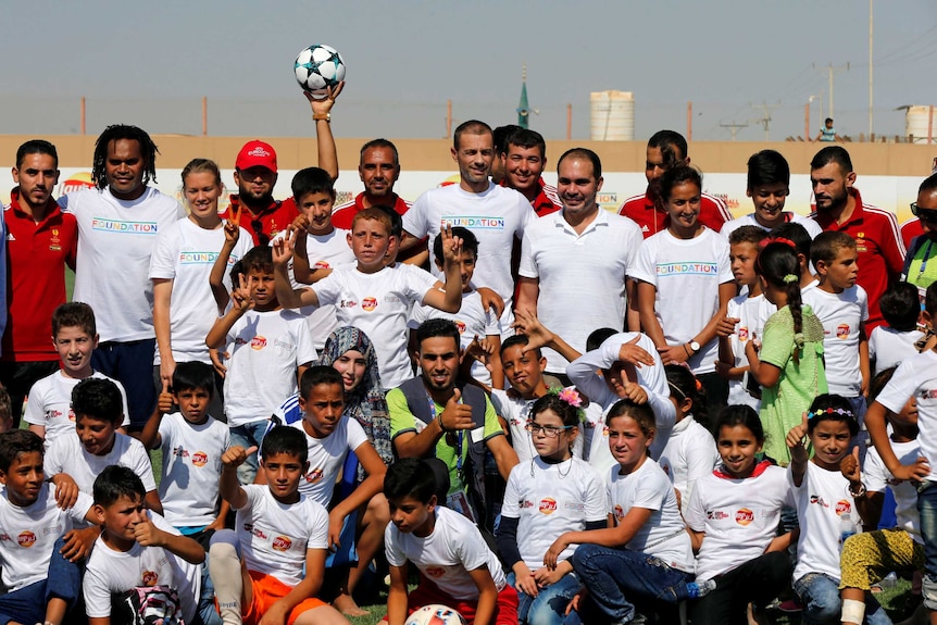 Refugees and football officials pose for a photo.