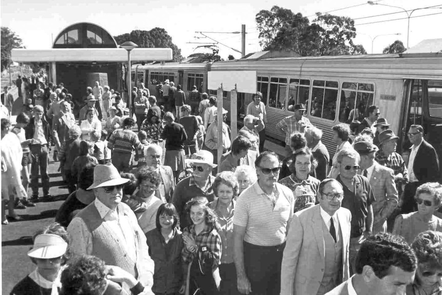 a crowd people on a railway platform with a train at the side