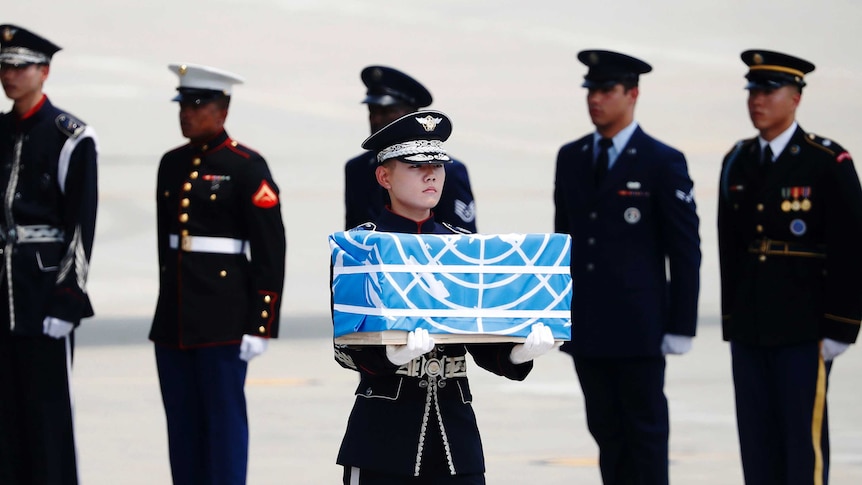 A soldier carries a casket draped in the UN flag