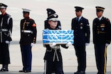 A soldier carries a casket draped in the UN flag