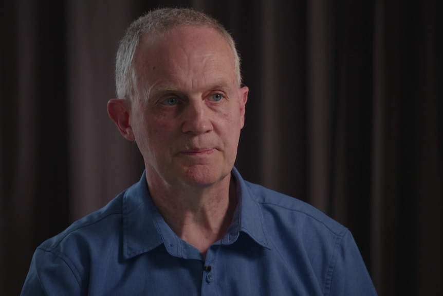 A middle-aged man in a collared shirt is interviewed.