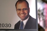 Daniel Lanzer's face on a sign hanging from an awning. Part of the clinic's phone number can be seen.