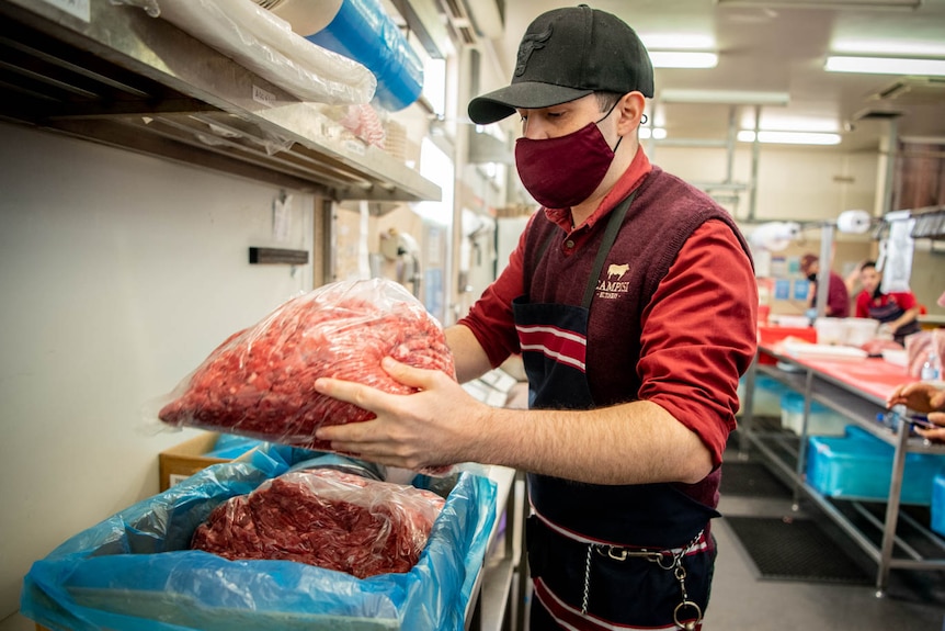 A Campisi Butchery staff member packs meat into a delivery box in the cutting room. 