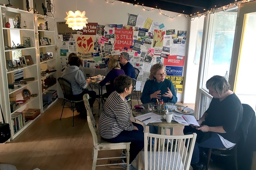 Two working groups with posters featuring slogans like "#Resist" and "The Future Is Still Female" on the wall.