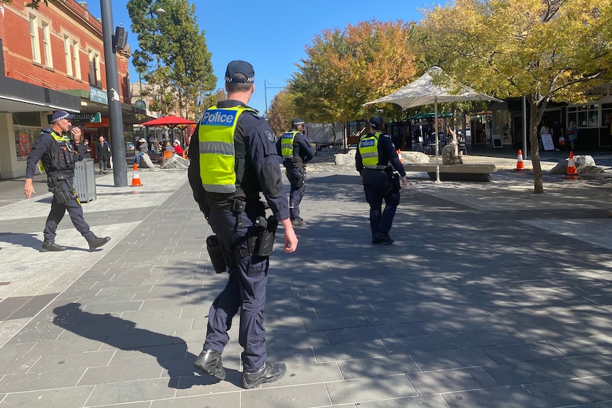 Police walk through an outdoor shopping mall 