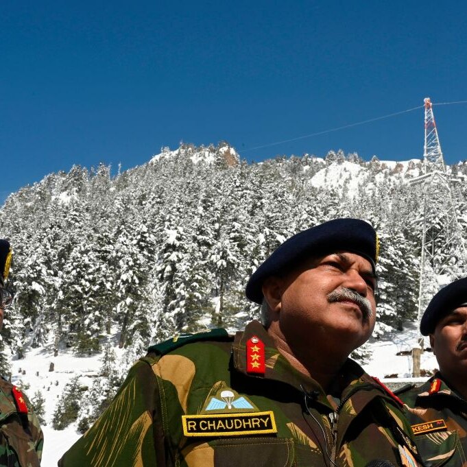 Three Indian army men near the Chinese border. A snowy mountain is in th background and deep blue sky