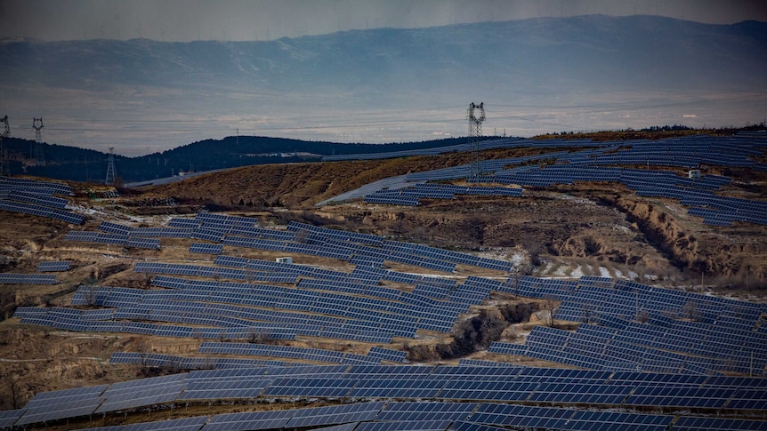 A birdseye view shows thousands of solar panels installed on hilly terrain in china