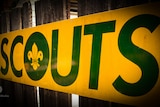 A Scouts sign on a wooden fence.