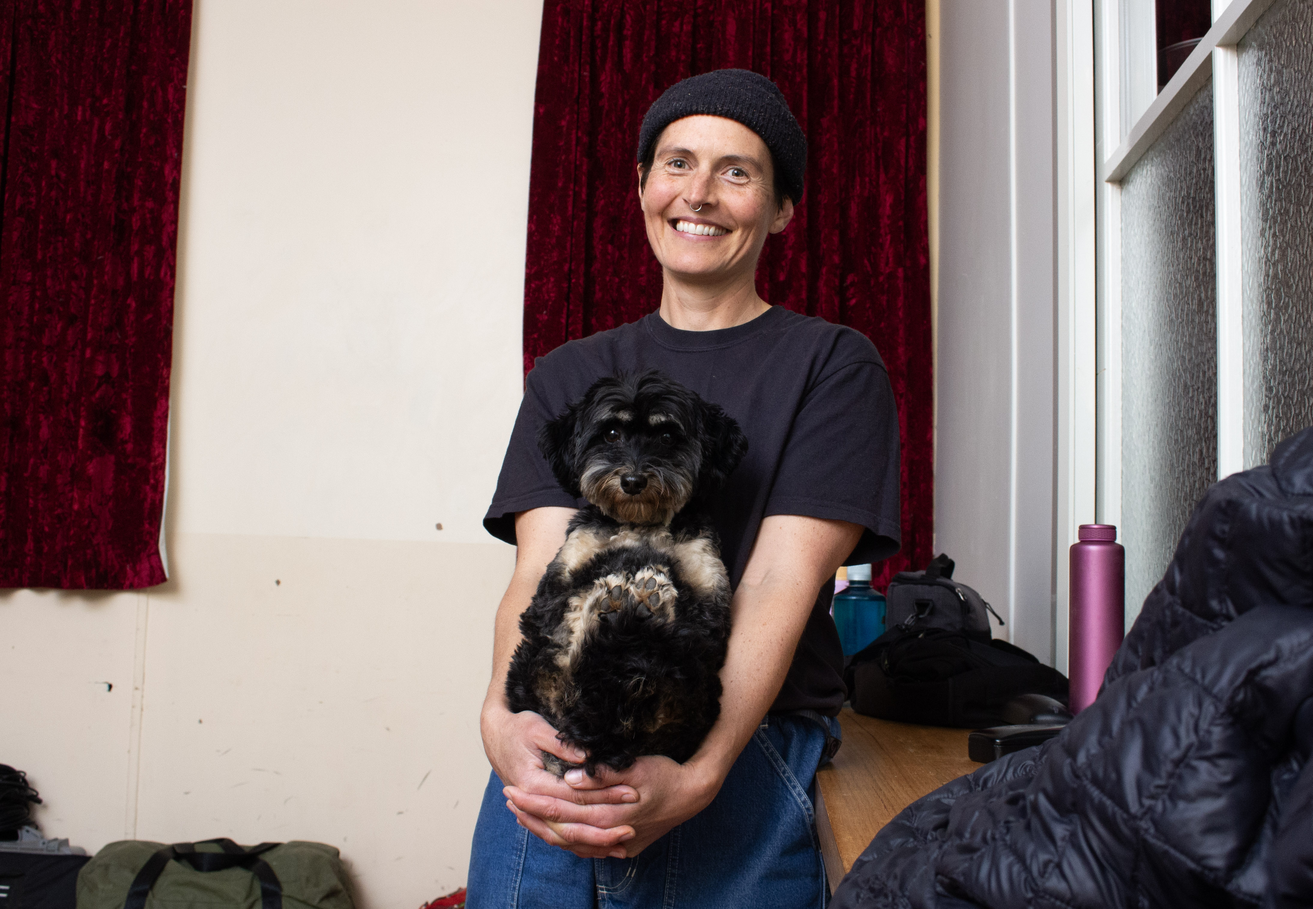 A person smiles holding a dog.
