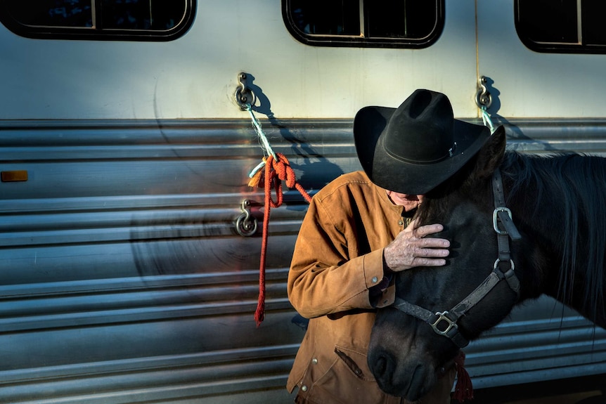 Against the backdrop of his trailer, Bob pats his horse.