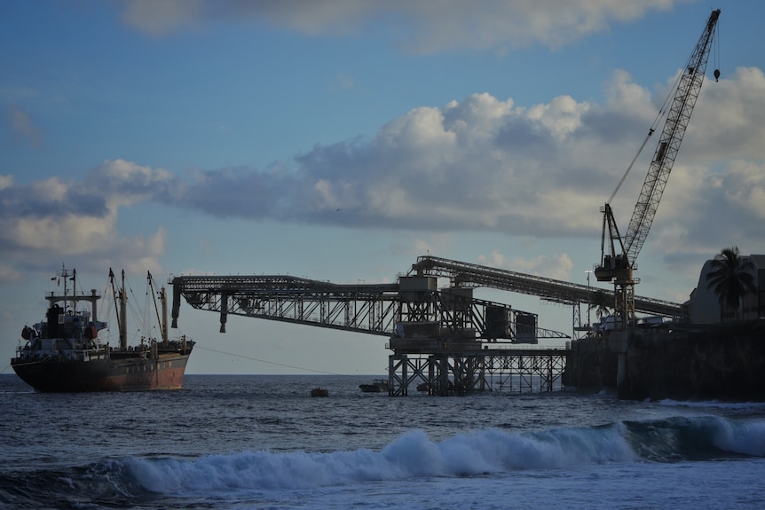 A boat on the water next to a mining operation.