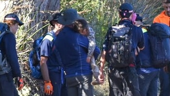 Shayla Phillips in arms of rescuers after being missing in Tasmanian bush.