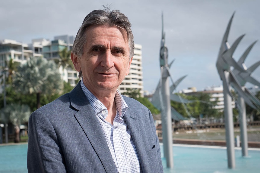 Daniel Gschwind stands at the Cairns lagoon with sculptures in the background.