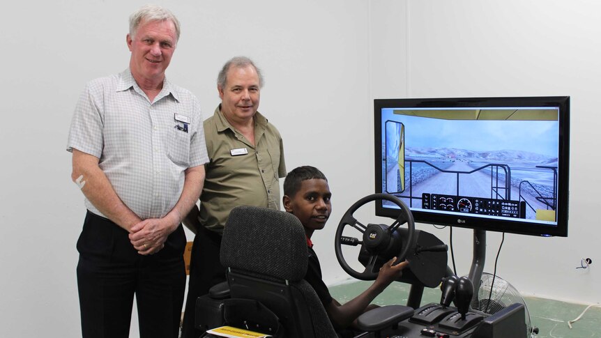 Yirara college principal David Ashcroft, teacher Gregory Miller and student Mishai Wollogorang standing with the simulator