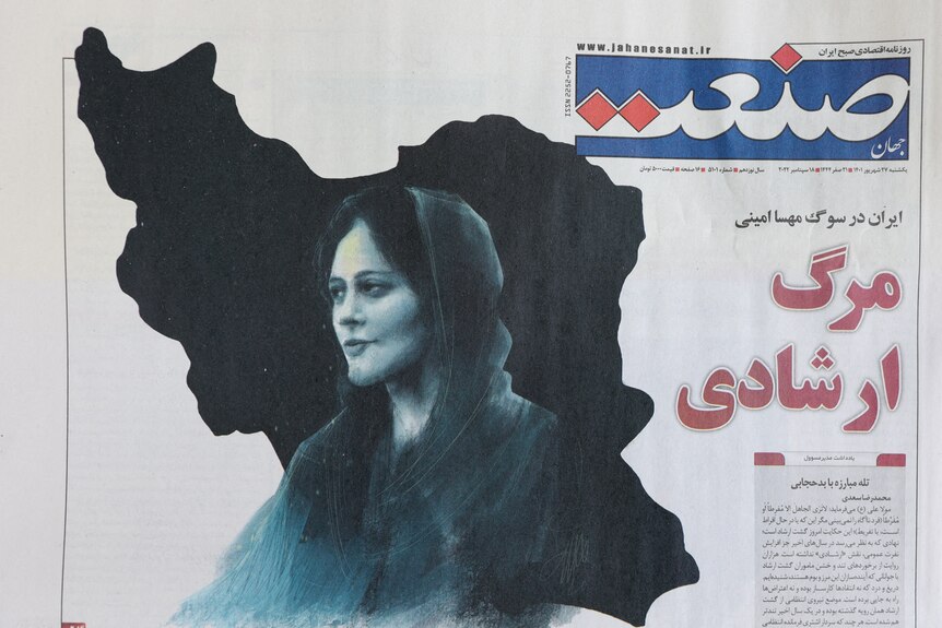 A newspaper with a cover picture of a woman with dark hair wearing a headscarf.