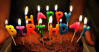 Birthday cake with candles spelling out Happy Birthday.