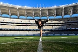 An umpire practises a centre bounce before an AFL match at Perth Stadium.