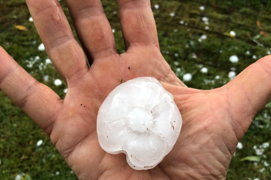 A large hail stone being held in a hand.