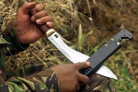 A man holds and sharpens a kukri knife.