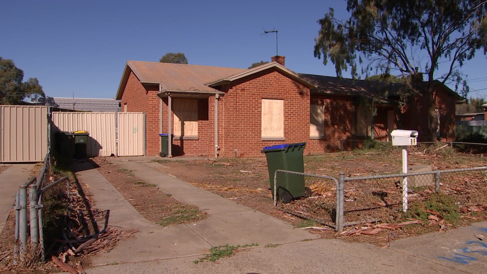 A small red brick house with wooden planks in the windows