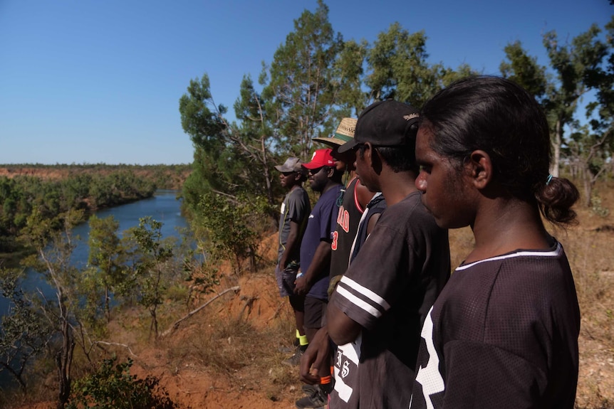 Camp participants stand in a row at the edge of the Robinson River.