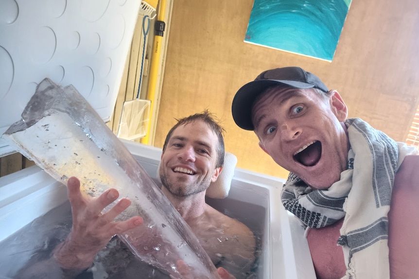 A man in an ice bath next to an excited man
