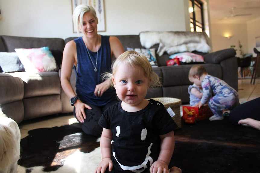 Alyssa Foster laughing in her loungeroom with her three children.