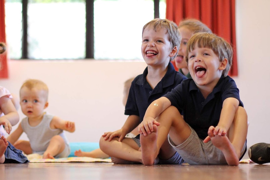 two young brothers sit next to each other poking their tongues out