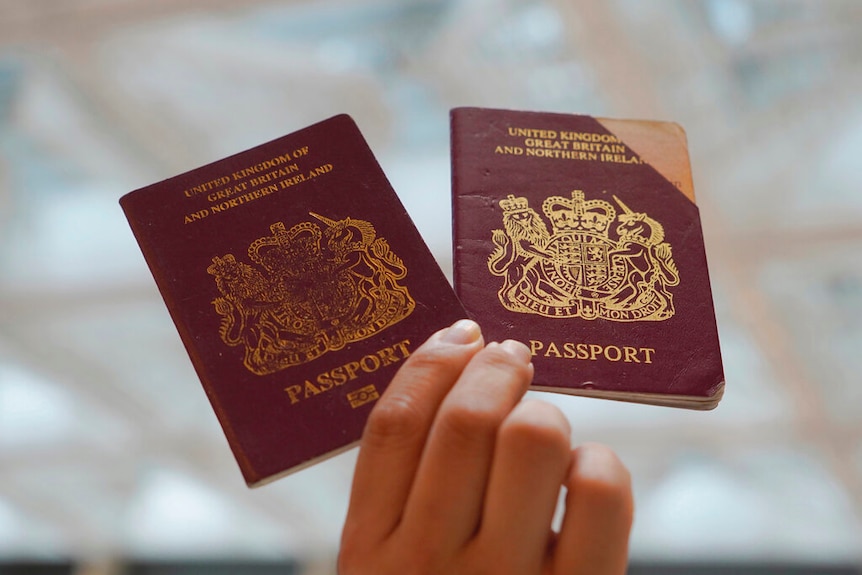 With a shallow depth of field, you few two maroon British passports, with one on the right being cut in its top-right corner.