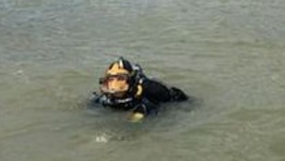 The head of a police diver is seen in a river.