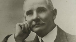 A black and white photo of a man resting his face on his hand