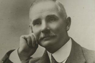 A black and white photo of a man resting his face on his hand