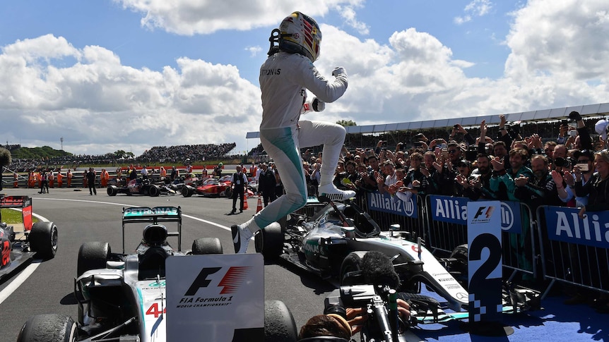 Lewis Hamilton jumps from a car as a huge crowd watches on, cheering