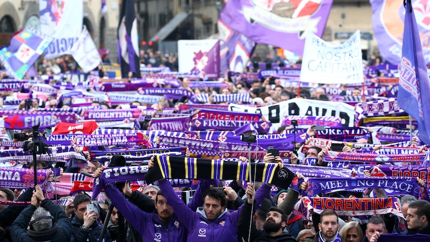Fans stand outside a church with Fiorentina scarves at Davide Astori's funeral in Florence.