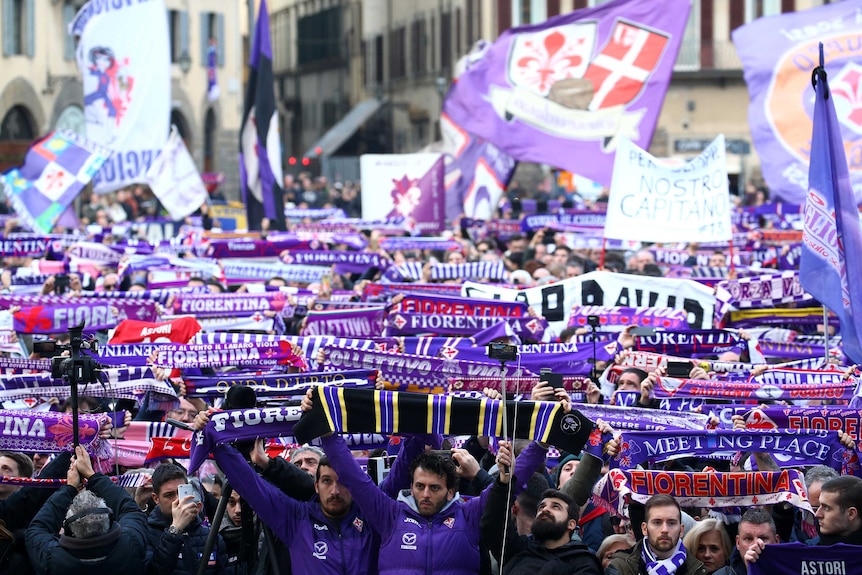 Fans stand outside a church with Fiorentina scarves at Davide Astori's funeral in Florence.
