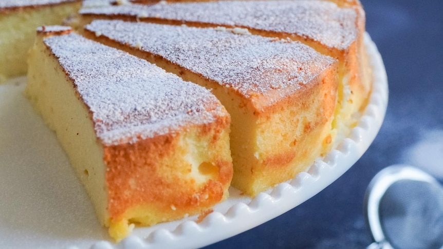 Cake with icing sugar on top, cut on cake stand