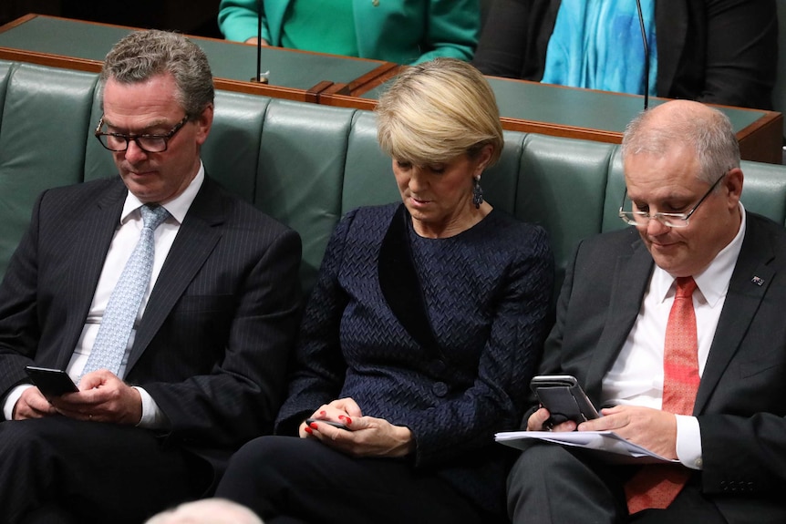 Christopher Pyne, Julie Bishop and Scott Morrison looking at their phones