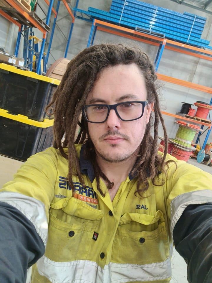 Una selfie de un hombre con gafas, coletas y un uniforme de alta visibilidad.