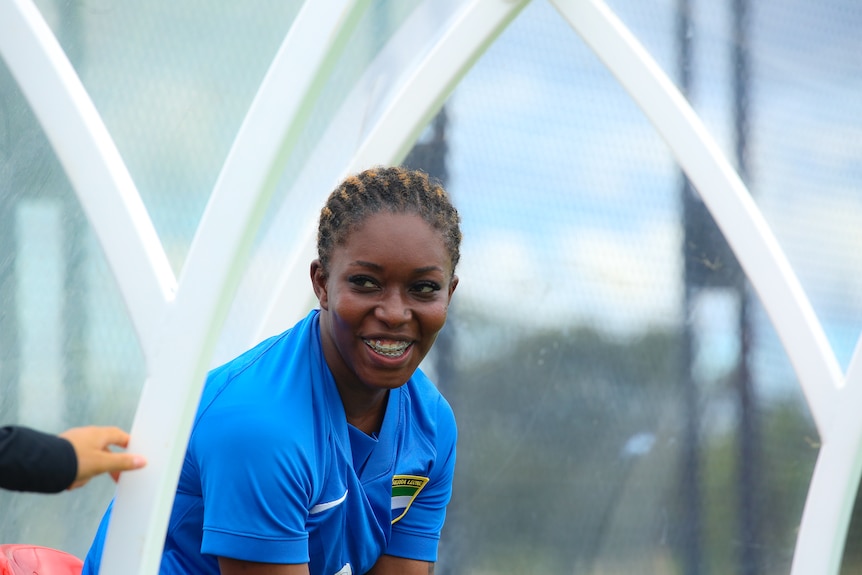 A woman is sitting and smiling to someone off camera.