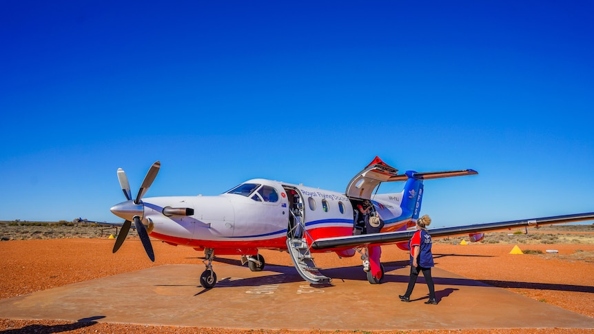 Royal Flying Doctor Service plane on red dirt runway, being unloaded of medical supplies