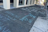 Chalk graffiti is sprawled across a sidewalk