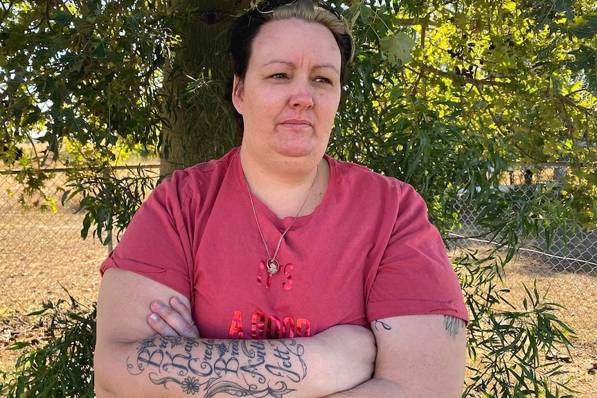 A woman standing in front of a tree with her arms crossed