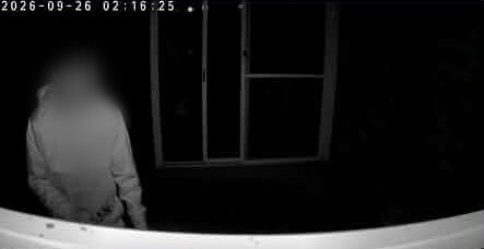 顔がぼやけている人物の白黒監視カメラ映像の静止画像。