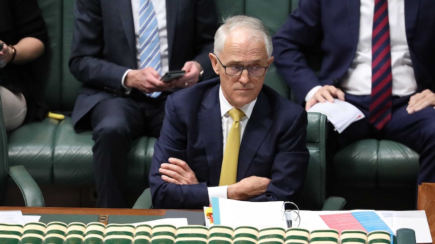 Malcolm Turnbull frowns, raises an eyebrow and crosses his arms across his chest.