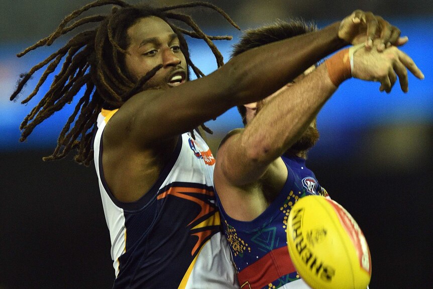 Nic Natanui with Tom Campbell with arms outstretched try to get a football